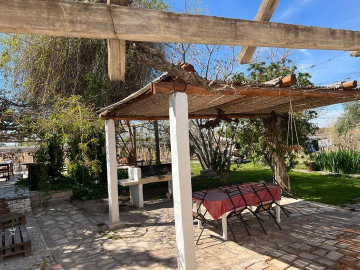 Quincho con techo de cañas, parrilla y mesa al aire libre