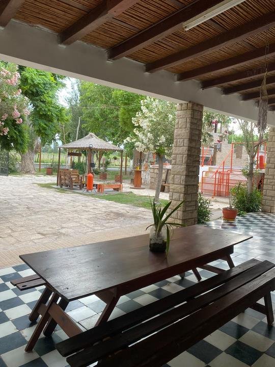 Galería techada con mesa de madera y vista al parque